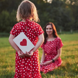 Mother Plays With Her Daughter On The Street In The Park At Sunset